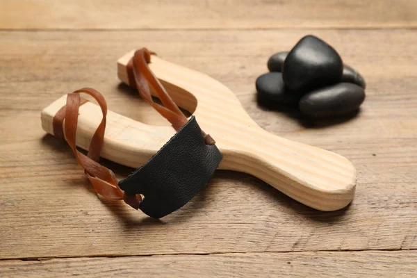 stock image Slingshot with stones on wooden table, closeup