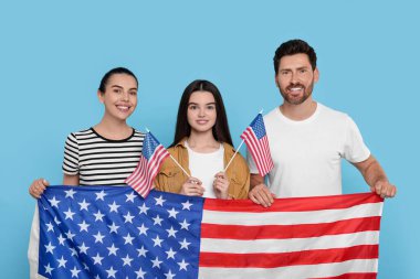4 Temmuz - ABD 'nin Bağımsızlık Günü. Açık mavi arka planda Amerikan bayrakları olan mutlu bir aile.