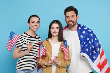 4 Temmuz - ABD 'nin Bağımsızlık Günü. Açık mavi arka planda Amerikan bayrakları olan mutlu bir aile.