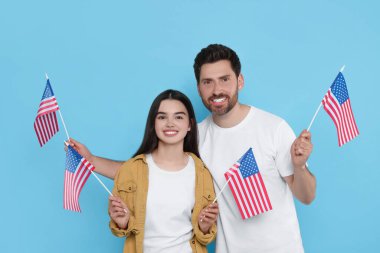 4 Temmuz - ABD 'nin Bağımsızlık Günü. Mutlu adam ve kızı açık mavi arka planda Amerikan bayrakları taşıyorlar.