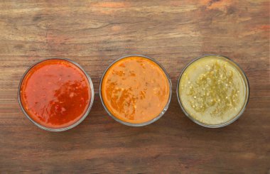 Farklı lezzetli salsa sosları ahşap masada, düz yerde.
