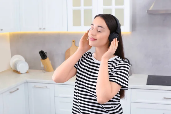 台所で音楽を楽しむヘッドフォンの美しい女性 — ストック写真