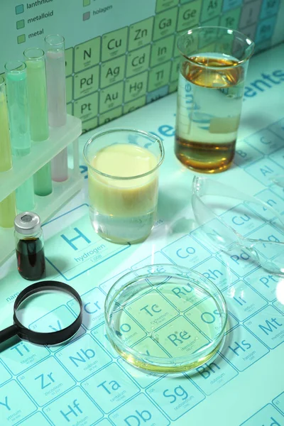 在化学元素周期表上有不同的装有液体和安全玻璃的实验室设备 浅绿色效果 — 图库照片