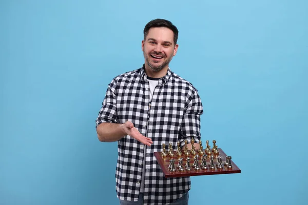 笑顔男ショーチェスボード上のゲームピースオンライトブルーの背景 — ストック写真