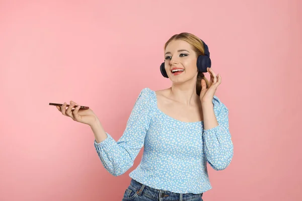 Ευτυχισμένη Γυναίκα Ακουστικά Απολαμβάνοντας Μουσική Και Κρατώντας Smartphone Ροζ Φόντο — Φωτογραφία Αρχείου