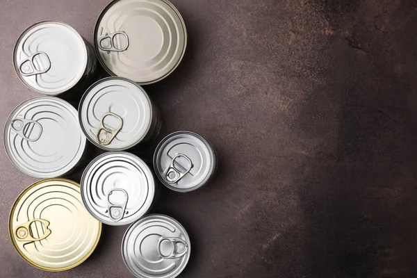 stock image Many closed tin cans on brown table, flat lay. Space for text