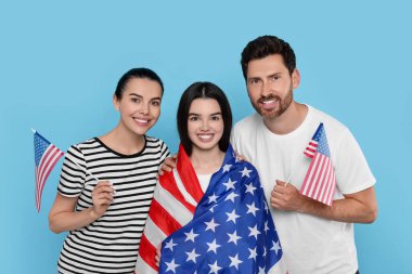 4 Temmuz - ABD 'nin Bağımsızlık Günü. Açık mavi arka planda Amerikan bayrakları olan mutlu bir aile.