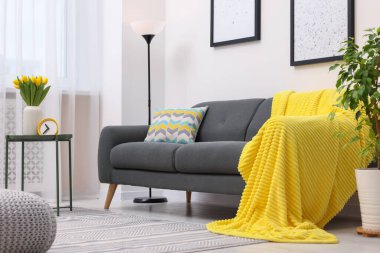 Spring atmosphere. Stylish living room interior with comfortable furniture and bouquet of beautiful yellow tulips