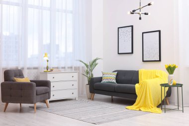 Spring atmosphere. Stylish living room interior with comfortable furniture and bouquet of beautiful yellow tulips