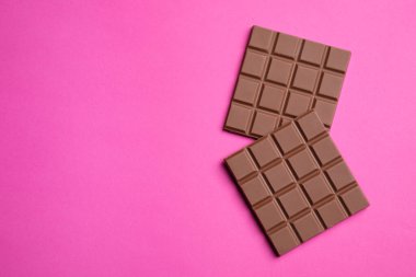 Pembe arka planda lezzetli sütlü çikolata parçaları. Metin için boşluk