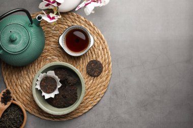Gri masanın üzerinde aromatik pu-erh çayı bulunan düz bir kompozisyon. Metin için boşluk