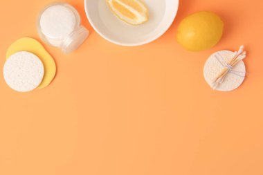 Limonlu yüz yıkama, taze narenciye ve soluk turuncu arka planda kişisel bakım ürünleri.