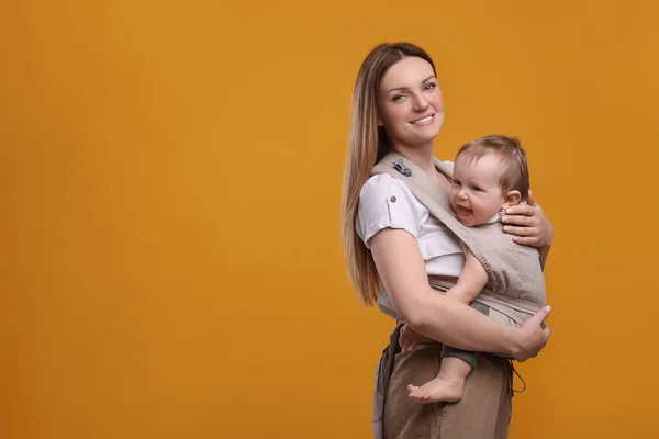 Moeder Houdt Haar Kind Draagdoek Babydrager Oranje Achtergrond Ruimte Voor — Stockfoto