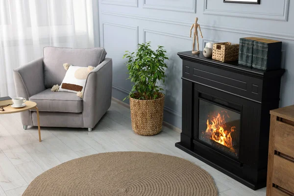 居心地の良いリビングルームで鉢植えやアームチェアの近くに黒いスタイリッシュな暖炉 — ストック写真