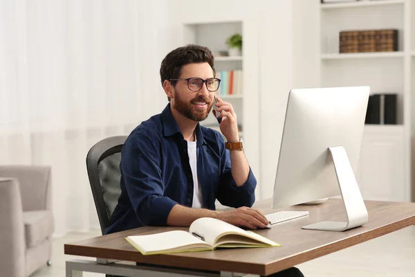 Işyerinde Odanın Ahşap Masasında Bilgisayarla Çalışırken Akıllı Telefondan Konuşan Mutlu — Stok fotoğraf