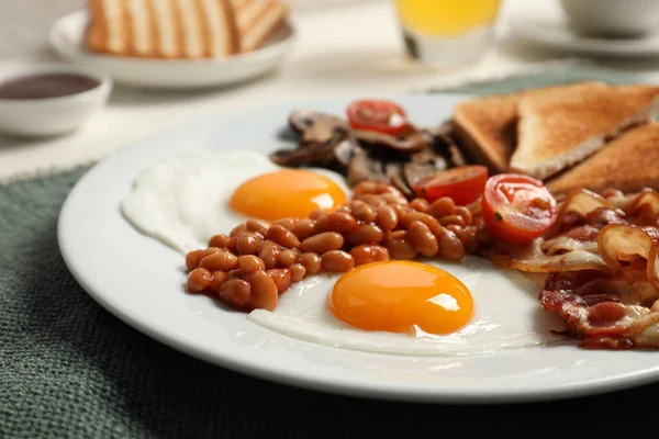 揚げ卵とプレート キノコ トマト ベーコンとテーブルの上にトースト クローズアップ 伝統的な英語の朝食 — ストック写真