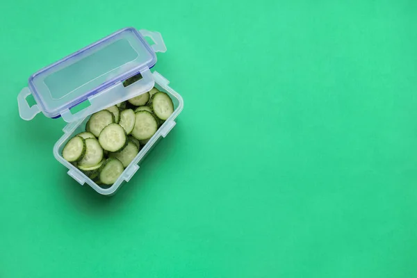 Kunststoffbehälter Mit Frisch Geschnittenen Gurken Und Deckel Auf Grünem Hintergrund — Stockfoto