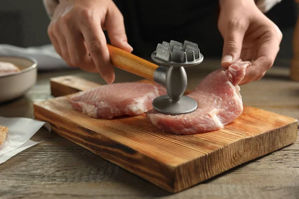 stock image Woman cooking schnitzel at wooden table, closeup