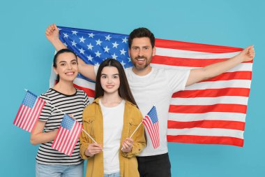 4 Temmuz - ABD 'nin Bağımsızlık Günü. Açık mavi arka planda Amerikan bayrakları olan mutlu bir aile.