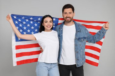 4 Temmuz - ABD 'nin Bağımsızlık Günü. Gri arka planda Amerikan bayrağı taşıyan mutlu çift
