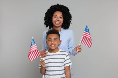 4 Temmuz - ABD 'nin Bağımsızlık Günü. Açık gri arka planda Amerikan bayrakları olan mutlu kadın ve oğlu