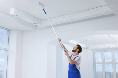 Odanın tavanını boyayan patenli tamirci