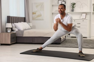 Adam evde spor paspası üzerinde sabah egzersizi yapıyor.