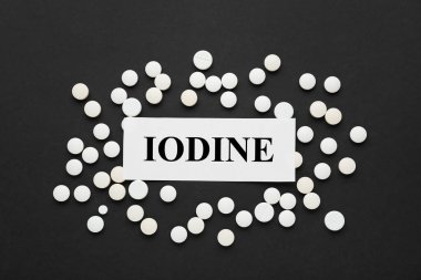 İyot elementli kart ve siyah arka planda haplar.