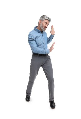 Şık giyinmiş olgun bir iş adamı beyaz arka plandaki bir şeyden kaçıyor.