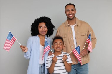 4 Temmuz - ABD 'nin Bağımsızlık Günü. Açık gri arka planda Amerikan bayrakları olan mutlu bir aile.