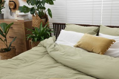 Rahat bir yatak ve yatak odasında güzel yeşil bitkiler.