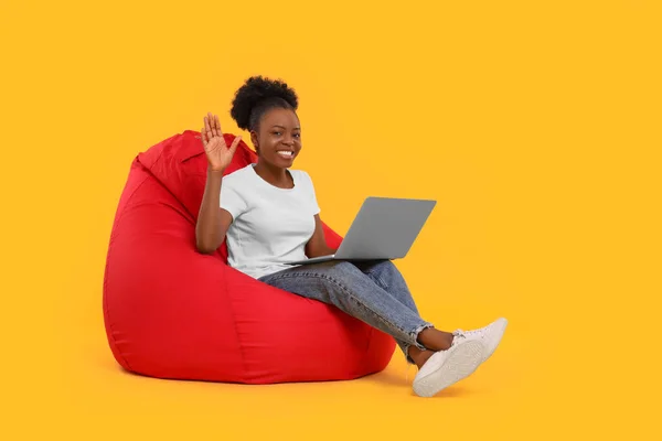 Όμορφη Νεαρή Γυναίκα Φορητό Υπολογιστή Κάθεται Καρέκλα Beanbag Φόντο Πορτοκαλί — Φωτογραφία Αρχείου