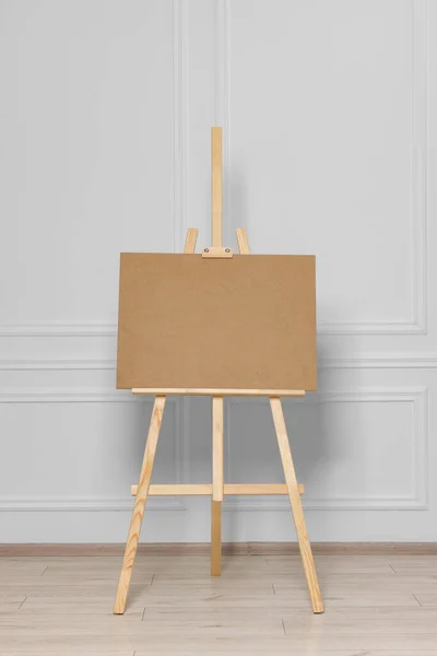 stock image Wooden easel with blank board near white wall indoors