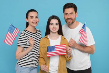 4 Temmuz - ABD 'nin Bağımsızlık Günü. Açık mavi arka planda Amerikan bayrakları olan mutlu bir aile.