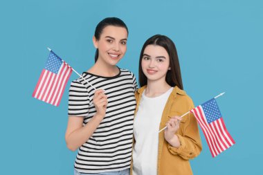 4 Temmuz - ABD 'nin Bağımsızlık Günü. Açık mavi arka planda Amerikan bayrakları olan mutlu kadın ve kızı