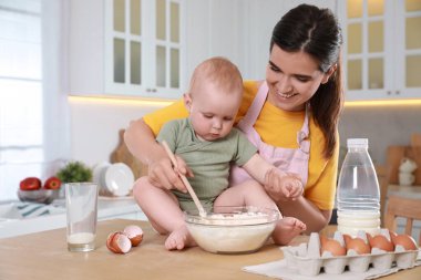 Mutlu genç kadın ve tatlı bebeği mutfakta birlikte para kazanıyorlar, mesaj atmak için yer var.