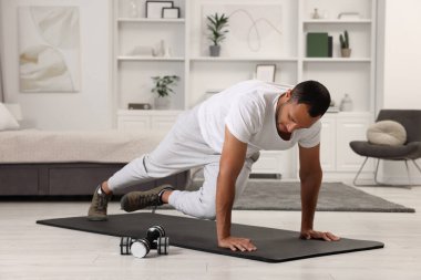 Adam evde spor paspası üzerinde sabah egzersizi yapıyor.