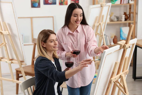 stock image Artist and her student with glasses of wine having painting class in studio. Creative hobby