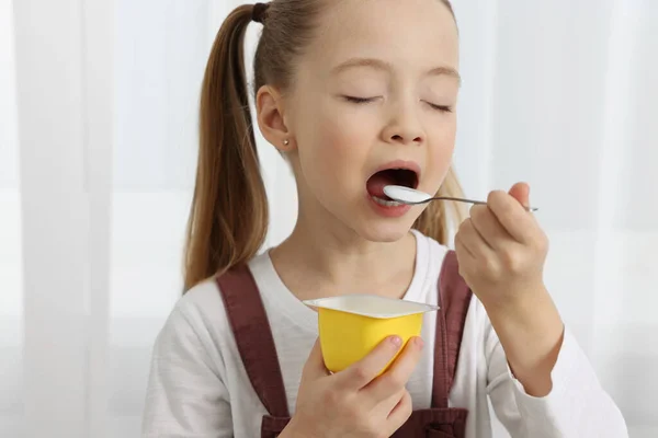 可爱的小女孩在室内享用美味的酸奶 — 图库照片