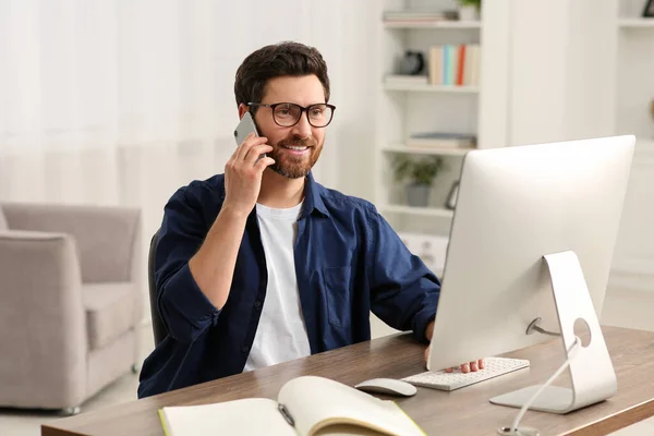 Işyerinde Odanın Ahşap Masasında Bilgisayarla Çalışırken Akıllı Telefondan Konuşan Mutlu — Stok fotoğraf