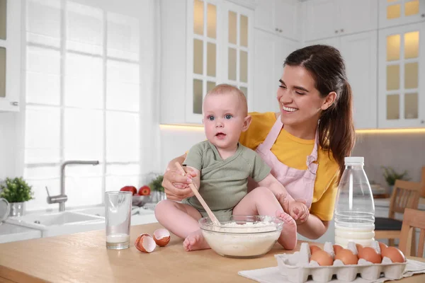 stock image Happy young woman and her cute little baby making dough together in kitchen, space for text