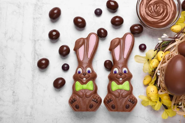 stock image Flat lay composition with chocolate Easter bunnies, eggs and candies on white textured table