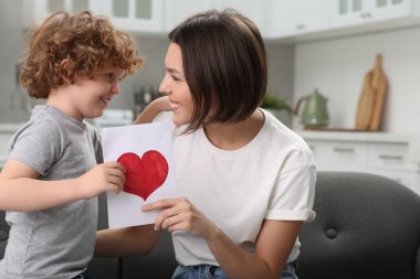 Anneler Günü 'nde annesini tebrik eden küçük bir çocuk. Elinde tebrik kartı tutan kadın.
