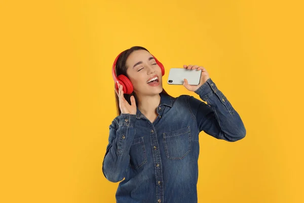 Šťastná Žena Sluchátkách Těší Hudbu Zpěv Smartphonu Oranžovém Pozadí — Stock fotografie