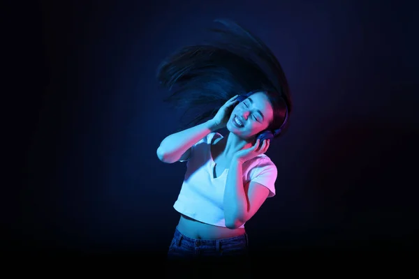 Szczęśliwa Kobieta Słuchawkach Słuchając Muzyki Tańcząc Neonach Ciemnoniebieskim Tle — Zdjęcie stockowe