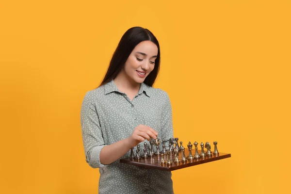 Счастливая Женщина Держит Шахматную Доску Играет Игровыми Фигурами Оранжевом Фоне — стоковое фото
