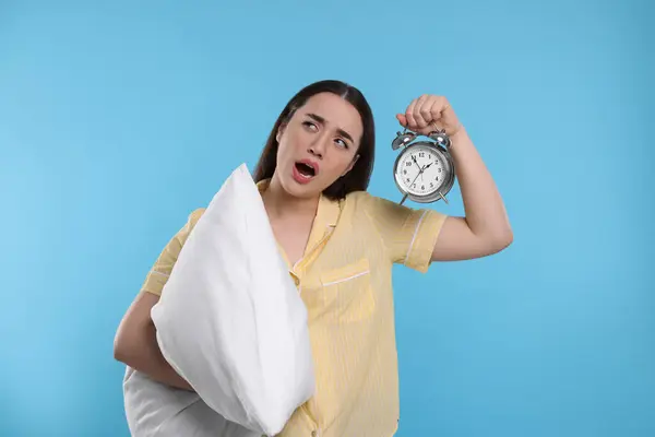枕と目覚まし時計の光の青の背景にあくびをして疲れ若い女性 不眠症の問題 — ストック写真