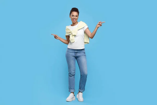 stock image Happy young woman in stylish eyeglasses dancing on light blue background