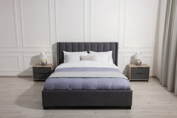 家でランプ付きのベッドサイドテーブルの間の快適なベッド インテリアデザイン — ストック写真
