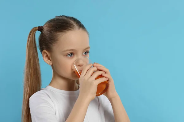小女孩喝淡蓝色背景的新鲜果汁 文字空间 — 图库照片